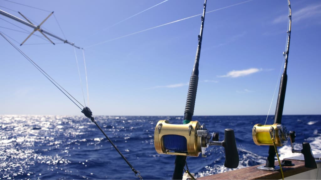 Fishing rods with reels are mounted on a boat, facing the ocean under a clear blue sky.